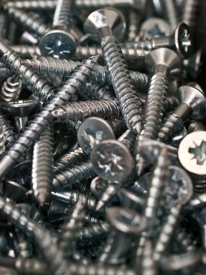 A detailed close-up shot of shiny metal screws in a pile, ideal for industrial and construction themes.