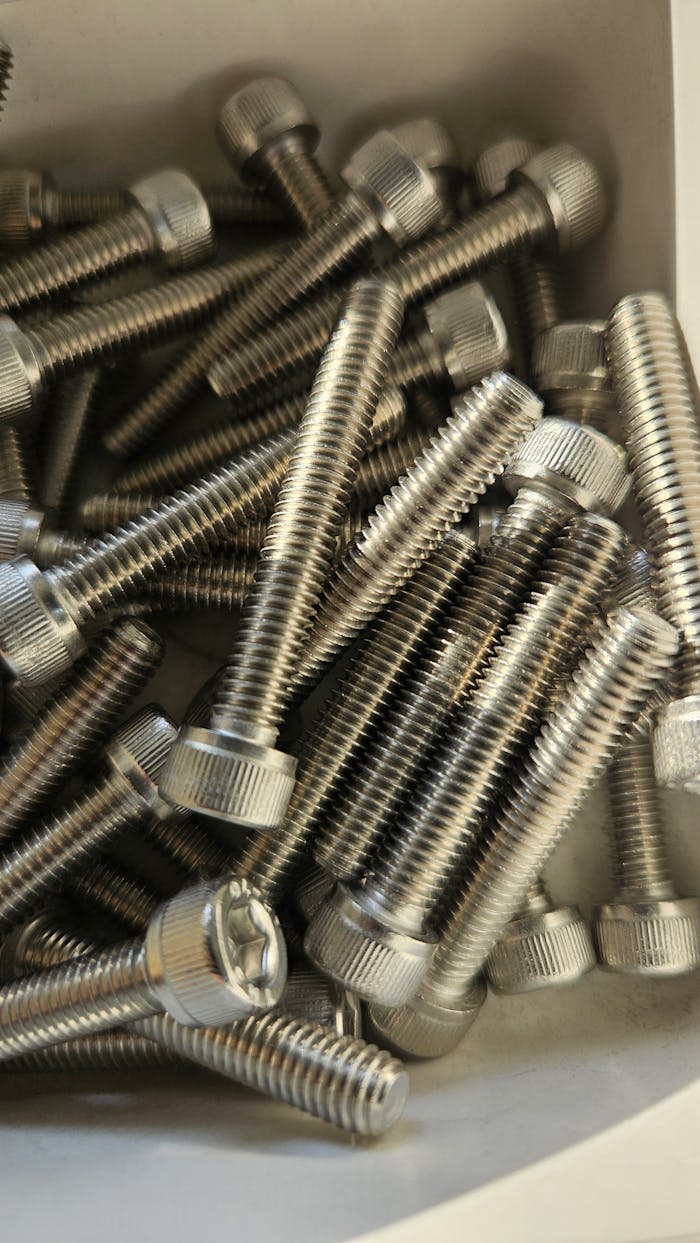 A detailed shot of stainless steel screws in a box, showcasing industrial hardware.